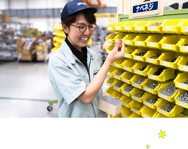 棚の前でネジを見る社員